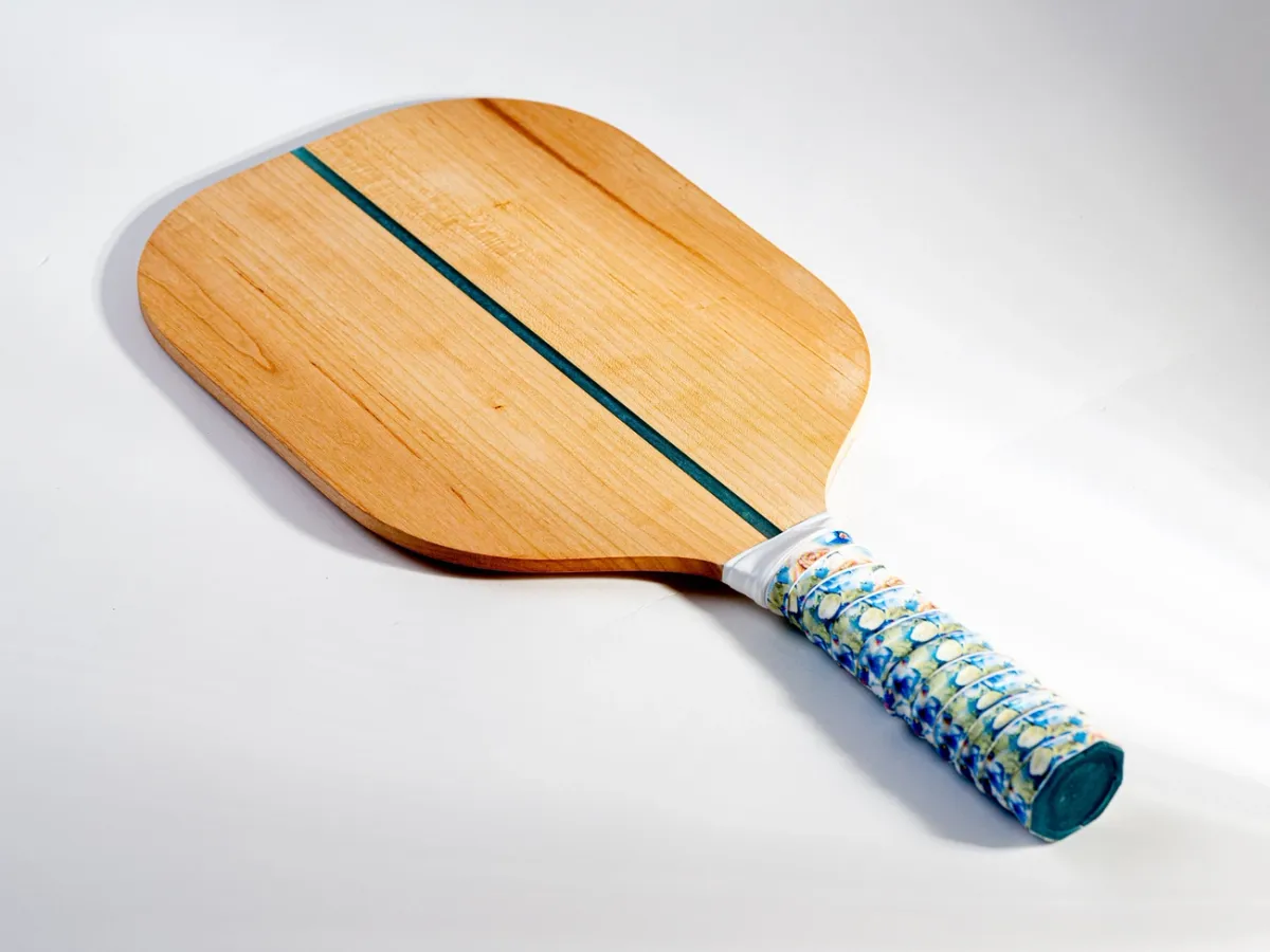 A wooden pickleball paddle on a light background, illustrating earlier paddle construction