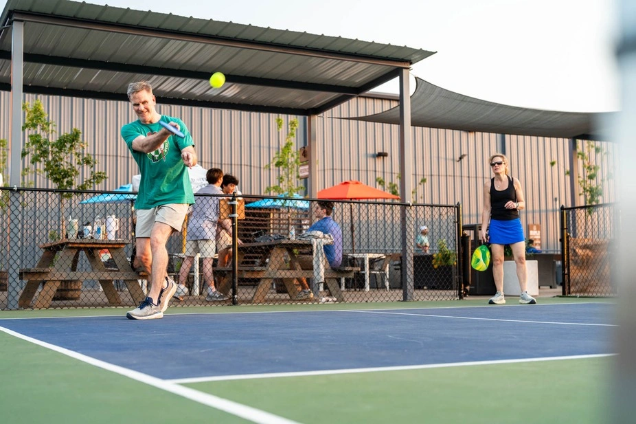 A male player demonstrating proper form while executing an offensive pickleball forehand drive during a recreational match. 