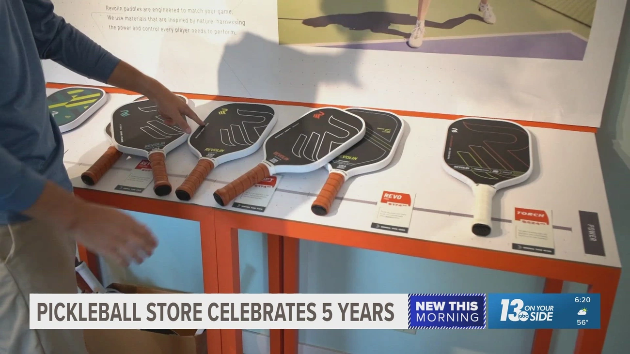 A customer in a pickleball store looking at a display of Revolin demo paddles 