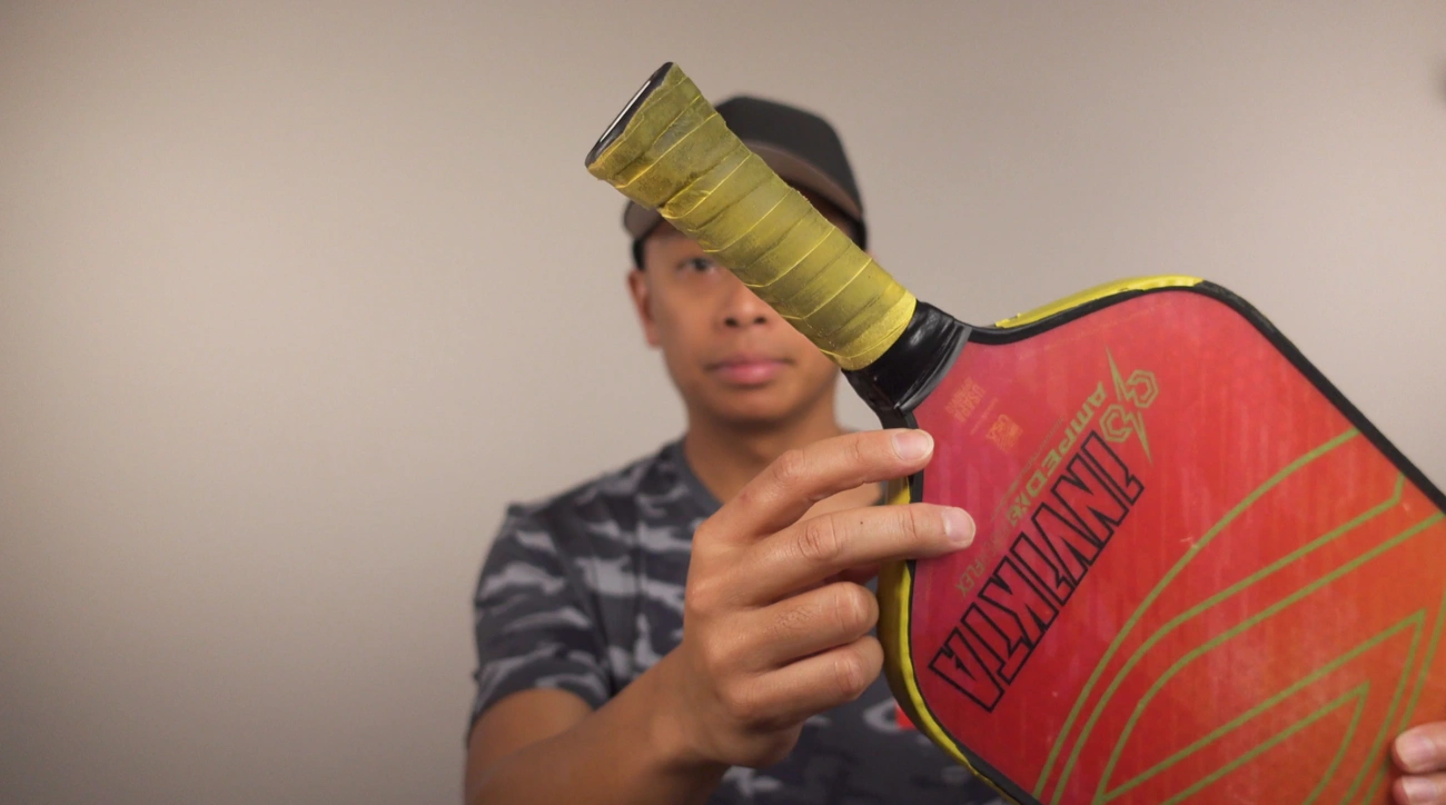 A player demonstrates removing grip material from a paddle handle.