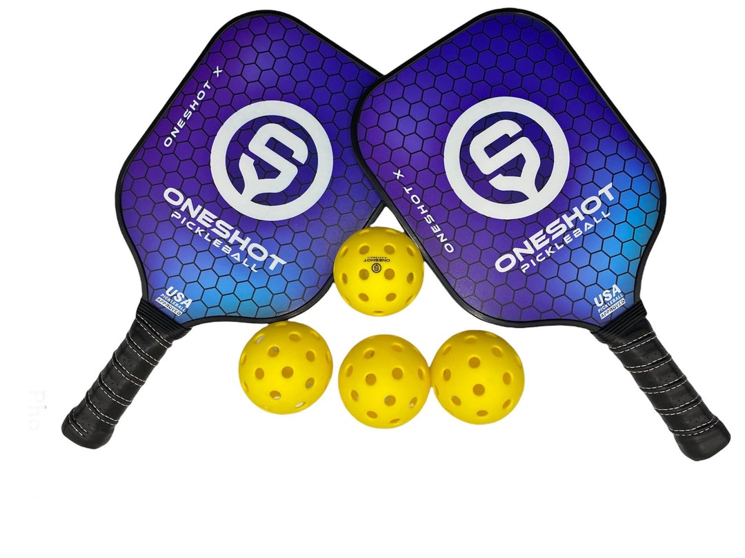 Two purple OneShot paddles lie beside four yellow pickleballs.