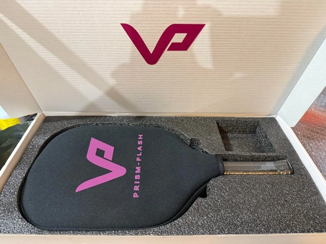 A black paddle with a pink logo rests inside a presentation box.
