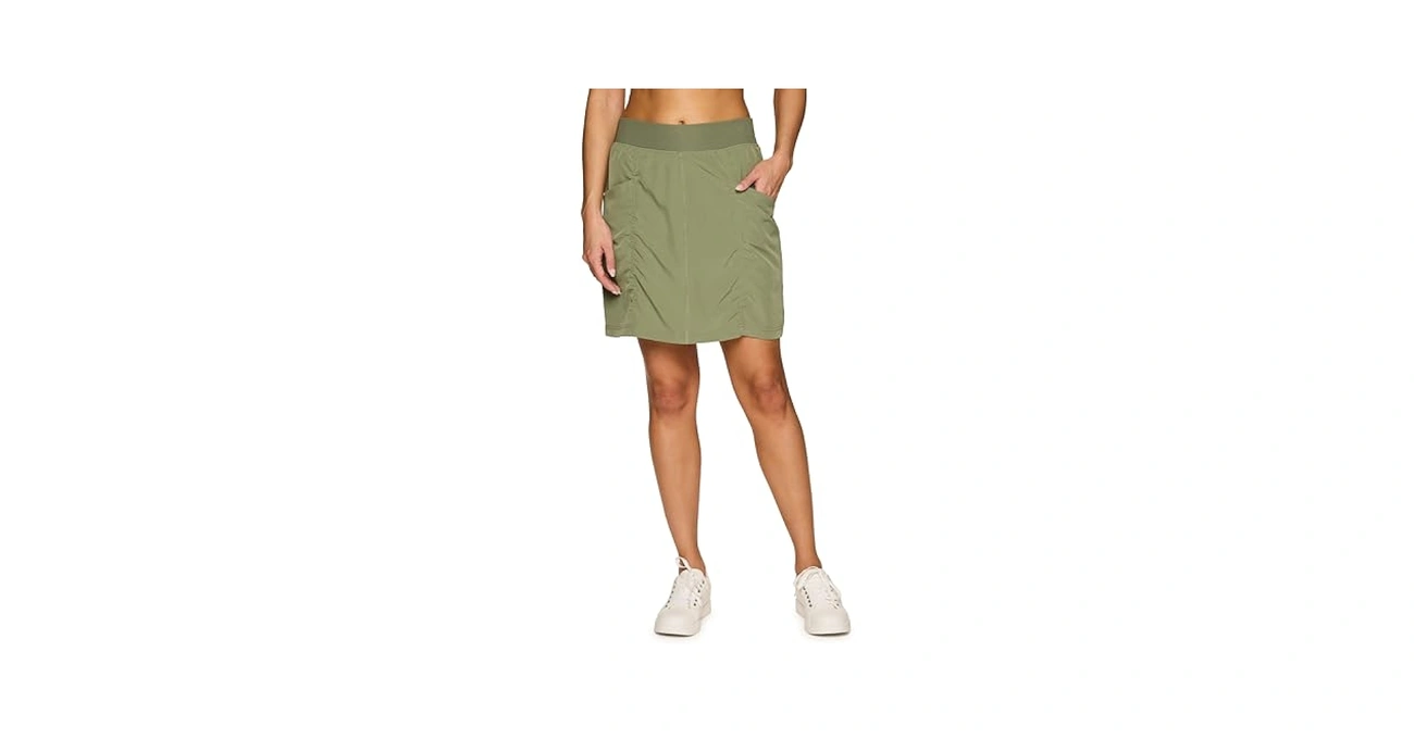 A model wears an olive athletic skirt and white shoes.