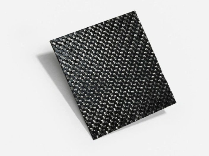 A square piece of woven carbon fiber fabric.