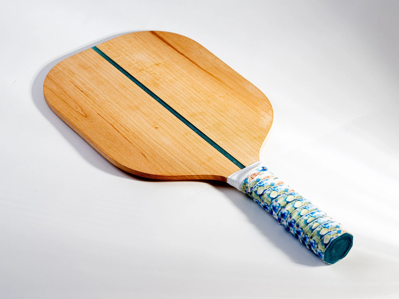 Wooden pickleball paddle with a blue stripe and a patterned grip on a white background