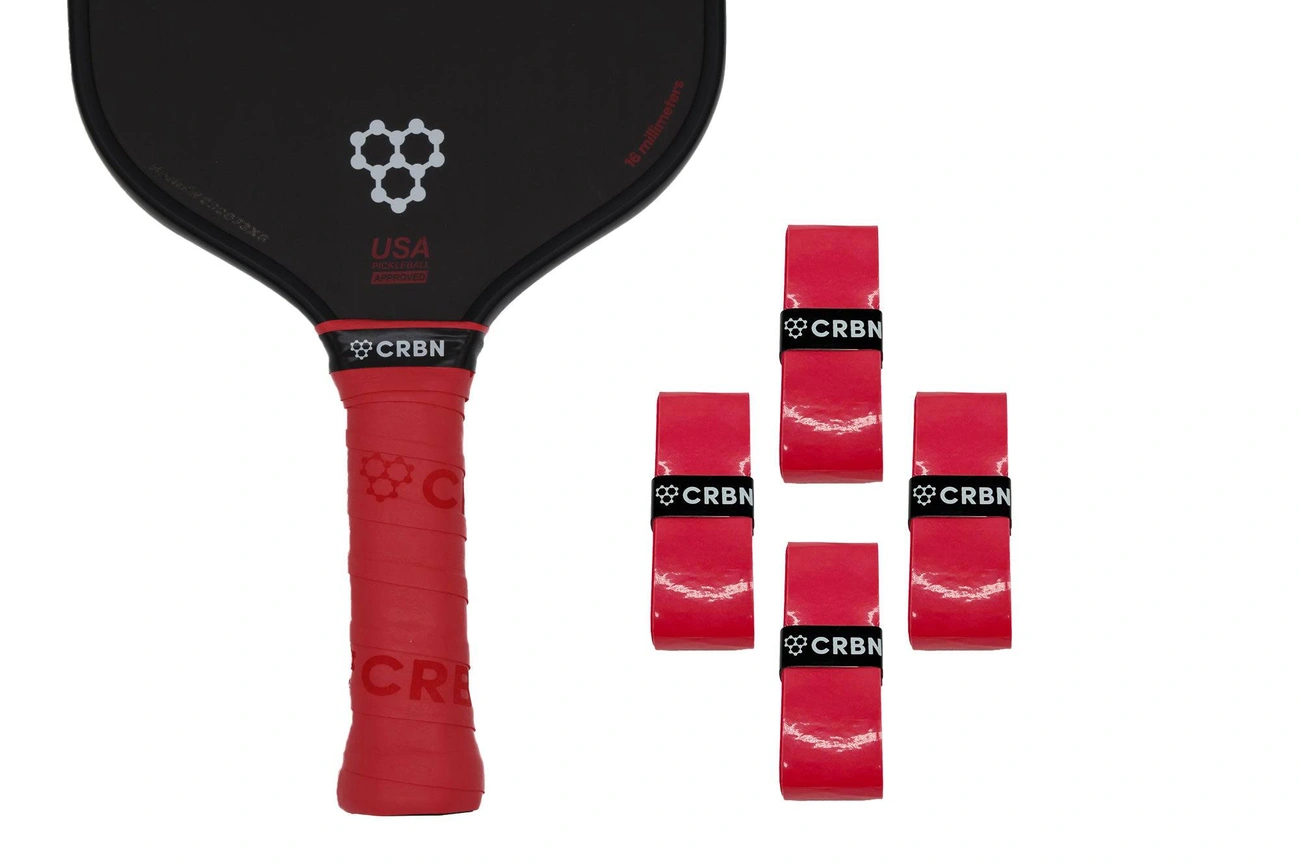 A black CRBN pickleball paddle with a red handle grip shown next to four matching red CRBN replacement overgrips, isolated on a white background.